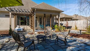 Un espace patio doté d’un sol en pierre, de mobilier d’extérieur et d’un coin salon abrité.
