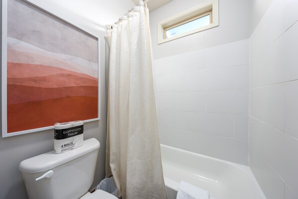 Ein Badezimmer mit Toilette, Duschvorhang und Badewanne.