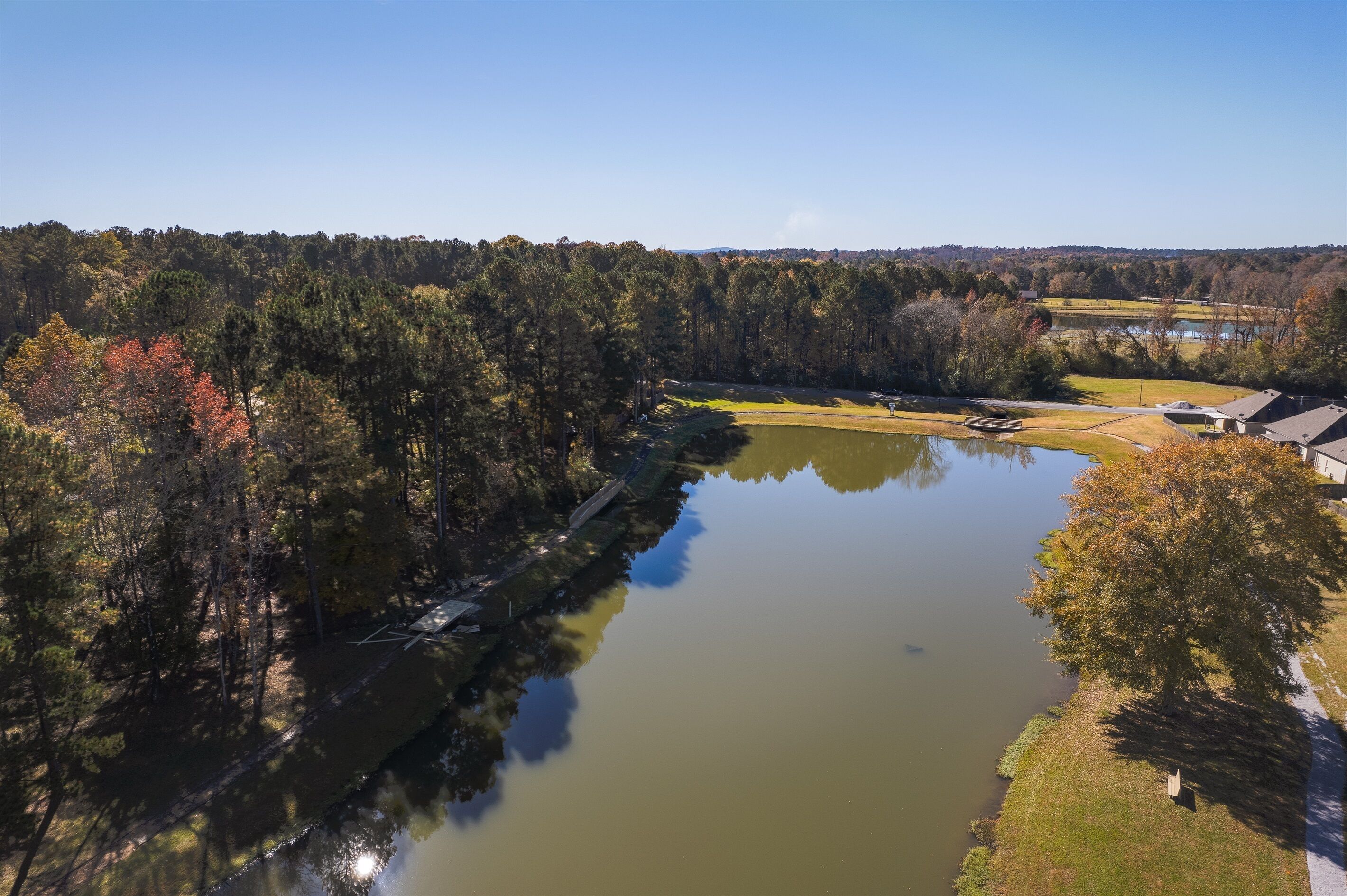 An aerial view of a lake surrounded by trees and a golf course.