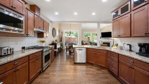 A modern kitchen with wooden cabinets, stainless steel appliances, and a central island. - Luxurious Retreat in SW Portland with 7-Person Hot Tub – Sleeps 14 Comfortably! (Portland)