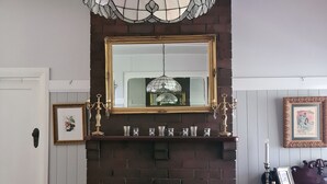 Ein Essbereich mit Kamin aus Backstein, einer Kristallleuchter und einem Spiegel darüber.