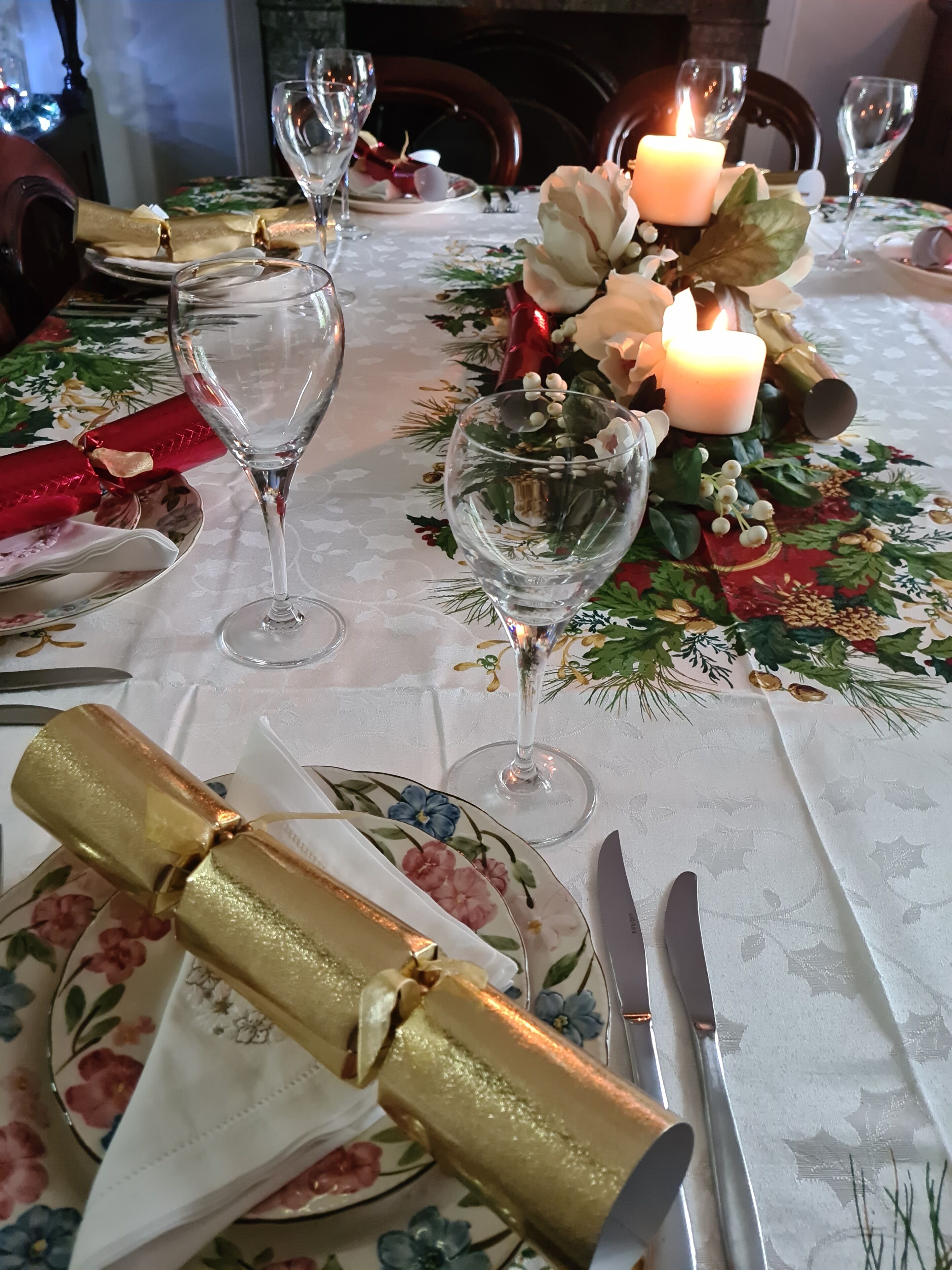 A table set for a meal with a floral tablecloth, candles, and a decorative centerpiece.