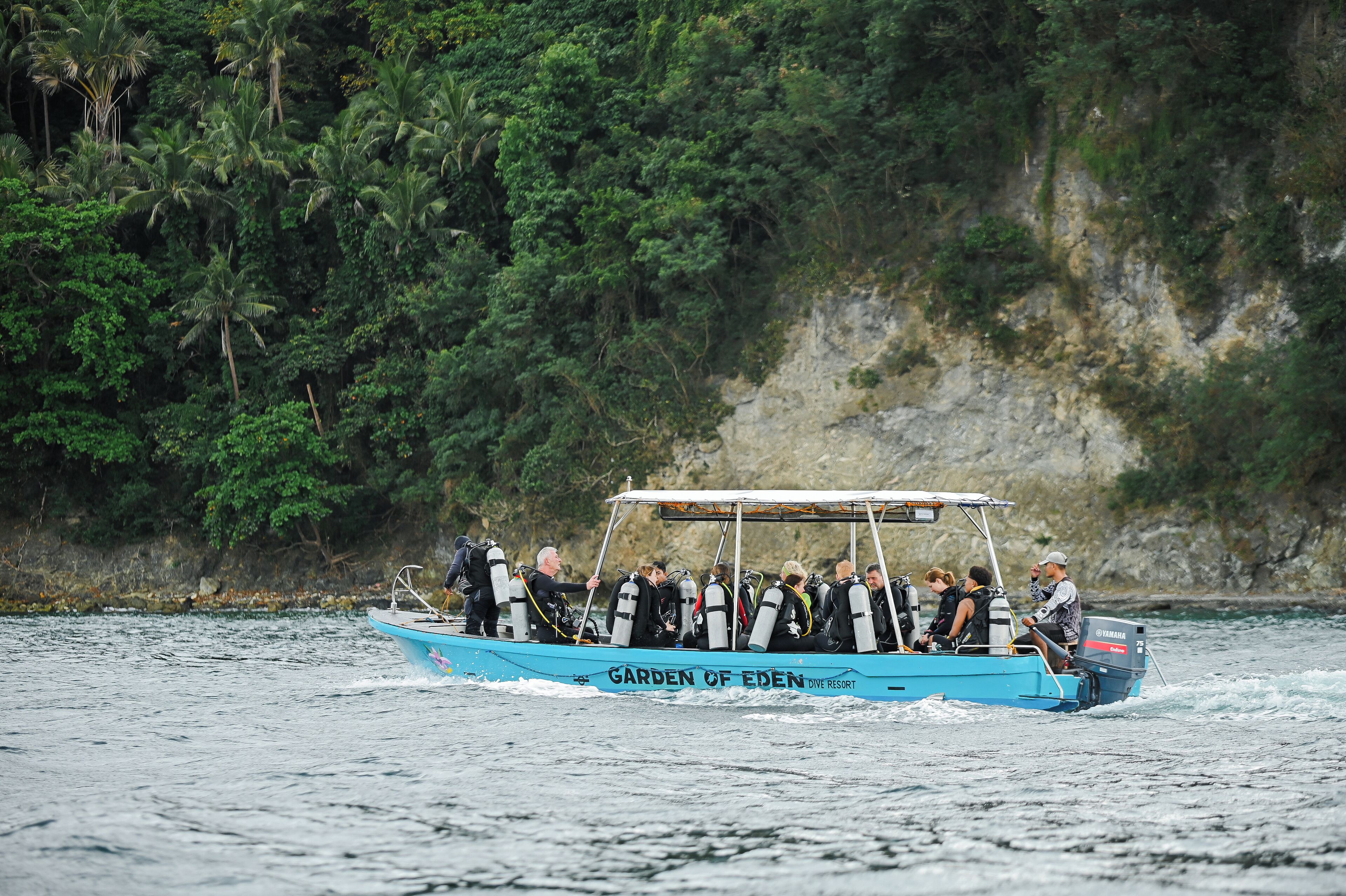 Un barco llamado 'Garden of Eden Dive Resort' con pasajeros que llevan equipo de buceo, indicando una actividad de buceo.