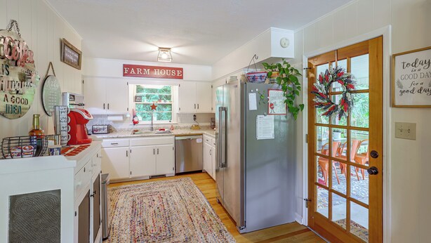 A kitchen with white cabinets, a stainless steel refrigerator, and a farmhouse sign. - Fire Pit & Game Room: Family Home in Marshall! (Marshall)