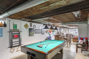 Une salle de billard équipée d’une table de billard, de queues et d’un porte-billes. Des panneaux sont accrochés aux murs, dont l’un indique : « ATTENTION : les billes sont fréquemment utilisées pour effectuer la première frappe ».