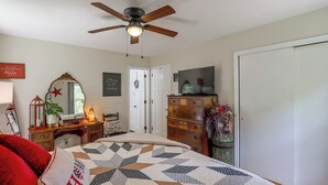 A bedroom with a bed, dresser, mirror, ceiling fan, and a television. - Fire Pit & Game Room: Family Home in Marshall! (Marshall)