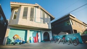 A building with a garage door, a bicycle rack, and surfboards outside. - MODERN SILVER STRAND BEACH HOUSE STEP2SAND SLEEPS 10 (Oxnard)