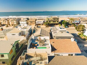 Un quartier résidentiel situé sur la côte, composé de plusieurs immeubles, dont certains sont dotés de terrasses sur le toit, et avec une plage en arrière-plan.