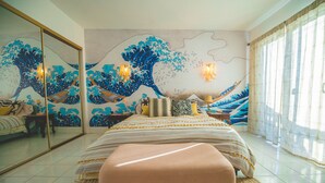 Un dormitorio con una cama grande, un espejo y un cuadro de una ola en la pared.