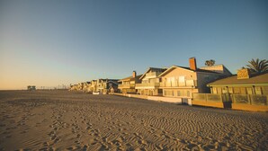 Propiedad frente a la playa con varias casas, playa de arena y cielo despejado.
