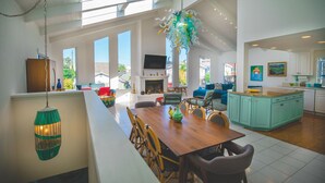 Amplia sala de estar con una mesa de comedor de madera, asientos cómodos y una cocina con armarios color turquesa.