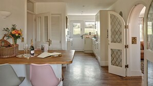 Une cuisine dotée d’un plan de travail en bois, de meubles blancs et offrant une vue sur l’extérieur.