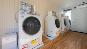 A row of white front-loading washing machines in a room with wooden flooring and white walls. - HOTEL R9 The Yard Kamisu (Kamisu)