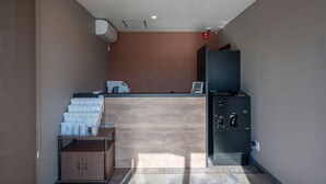 A reception area with a counter, a coffee machine, and a small seating area with a table and chairs. - HOTEL R9 The Yard Kamisu (Kamisu)