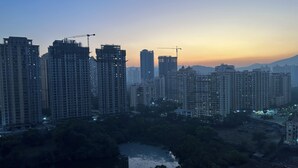 Un paisaje urbano con rascacielos, algunos en construcción, y una masa de agua al frente.
