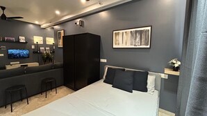 Un dormitorio moderno con cama, televisor, armario y escritorio.