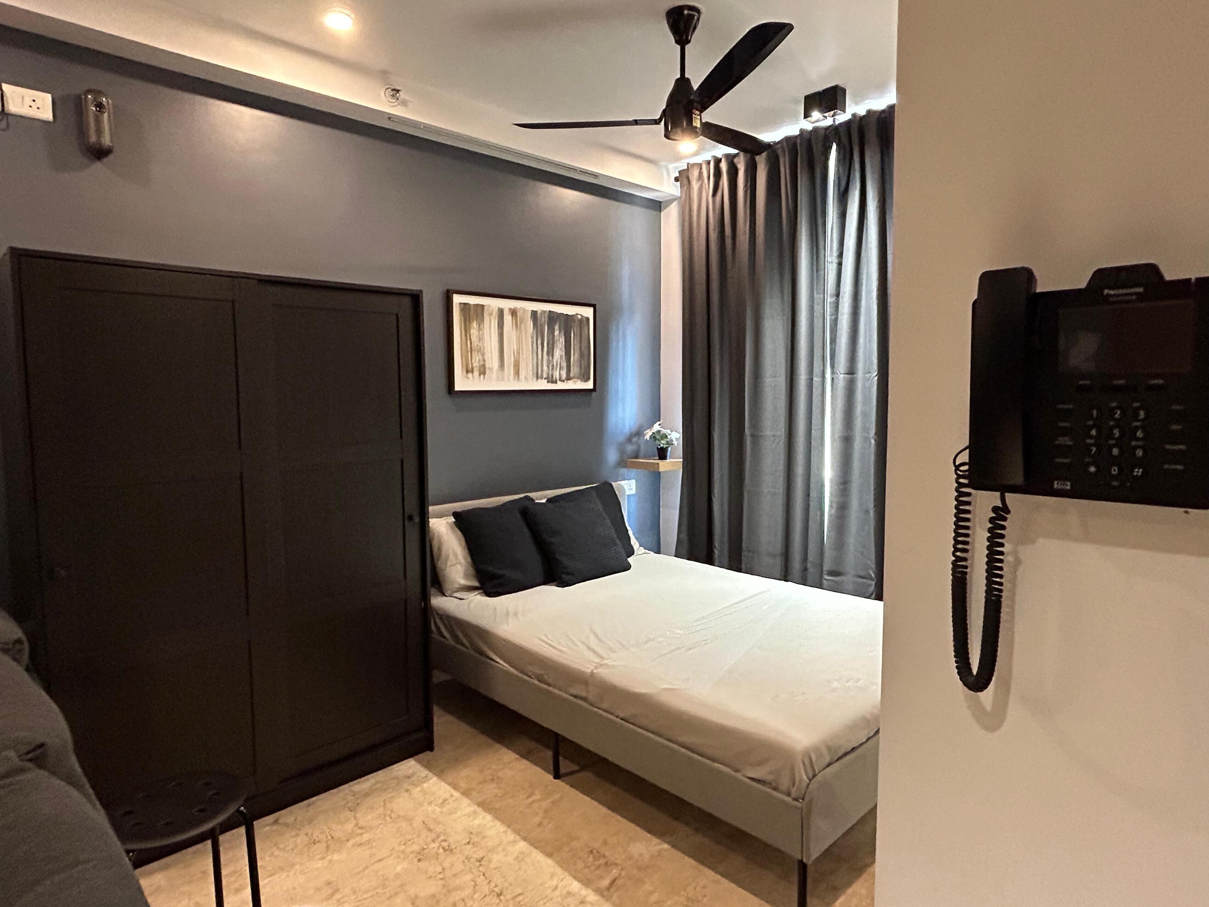 Ein Schlafzimmer mit Bett, Schrank, Deckenventilator, Telefon und einem Bild an der Wand.