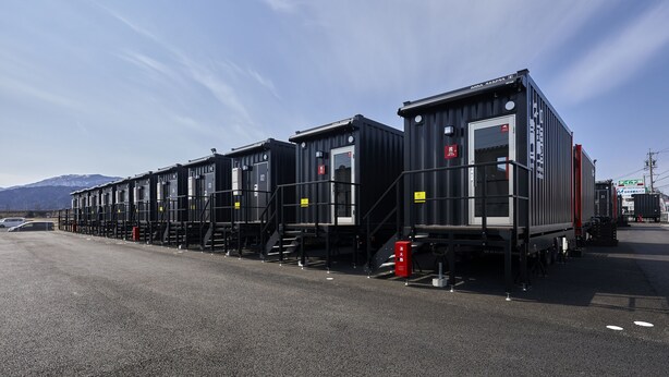 A row of black shipping containers arranged in a row with steps leading up to each one. - HOTEL R9 The Yard Tarui (Tarui)