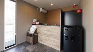 A reception area with a sliding glass door, a small counter with a coffee machine, and a black refrigerator. - HOTEL R9 The Yard Tarui (Tarui)