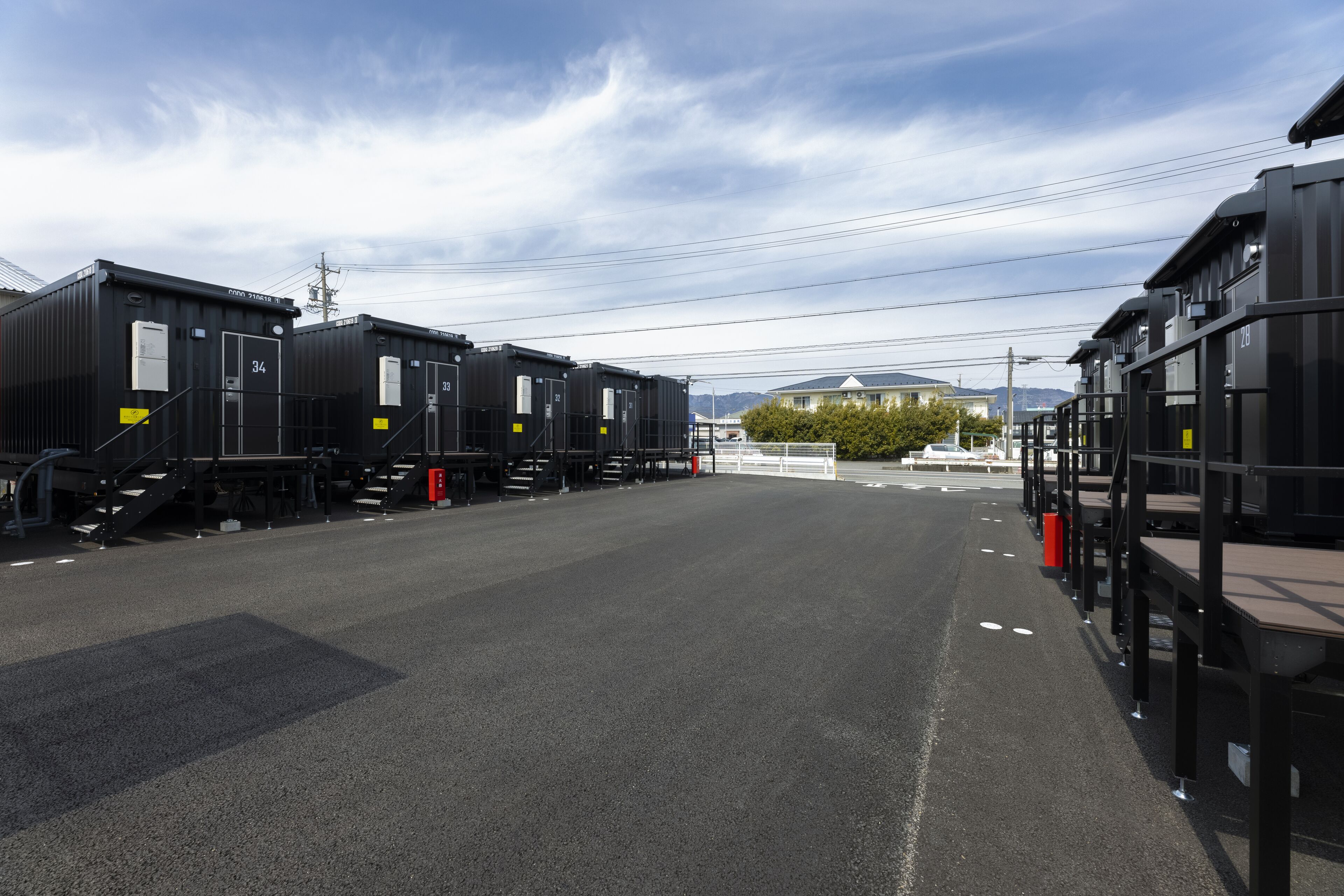 Ein Bahnhof mit mehreren schwarzen Zugwagen, die hintereinander geparkt sind, einem klaren Himmel und einem Gebäude mit einem grünen Dach im Hintergrund.