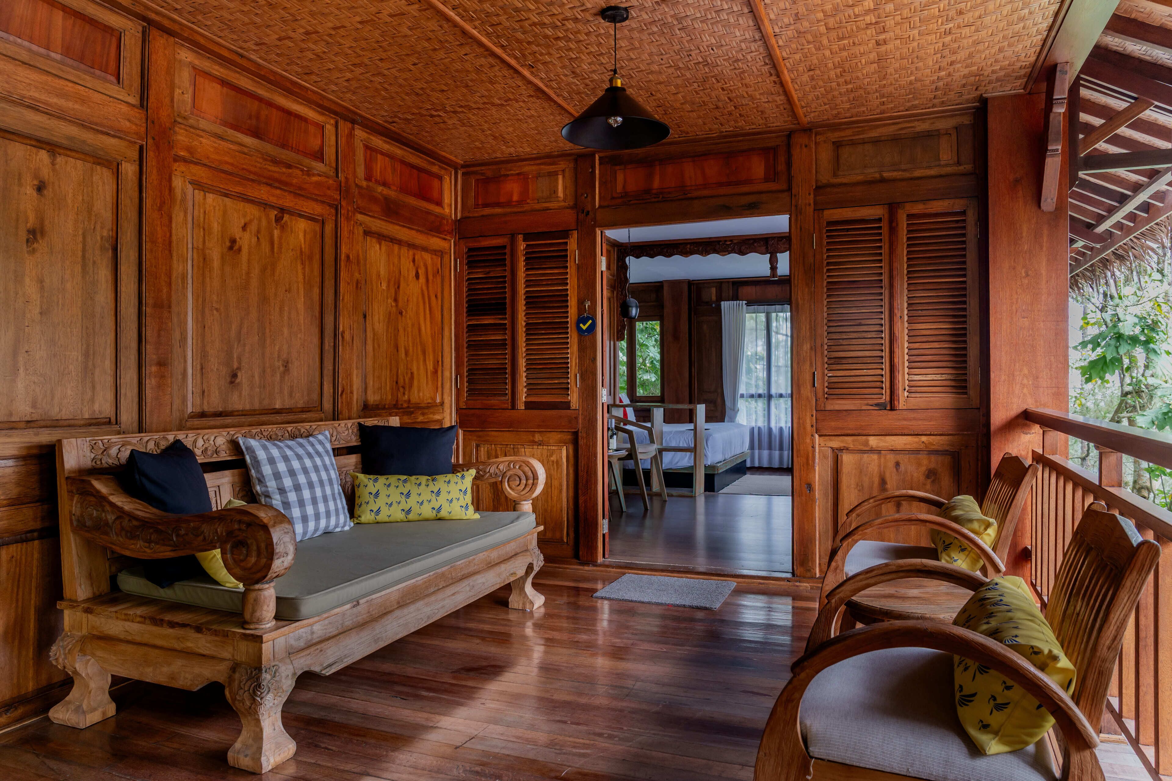 A wooden interior with a sofa, chairs, and a ceiling with a woven pattern.