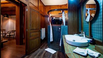 Un baño con detalles de madera, un espejo grande, un lavamanos y una zona de ducha.