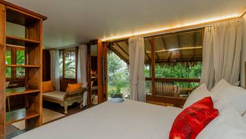 A room with a bed, a wooden desk, a chair, and a window with curtains.