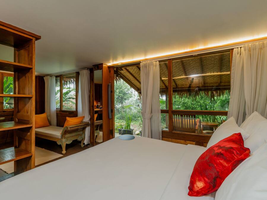 A room with a bed, a wooden desk, a chair, and a window with curtains.