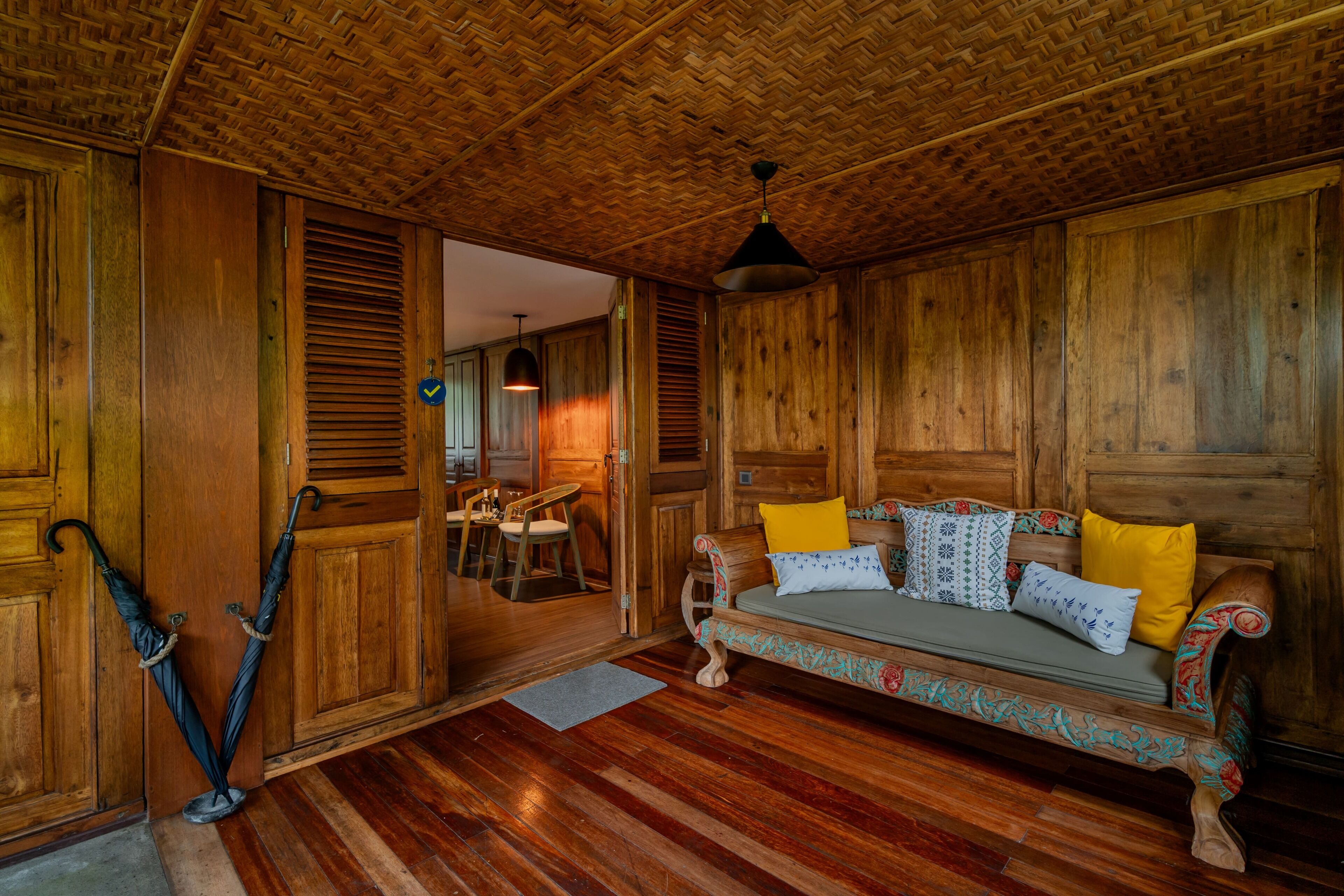 Interior de una cabaña de madera con sofá, cojines estampados y un comedor.