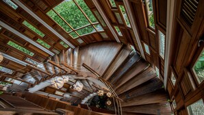 A spiral staircase with wooden railings and a view of greenery outside. - TIRA VILAGNA SUITES & SPA (Kintamani)