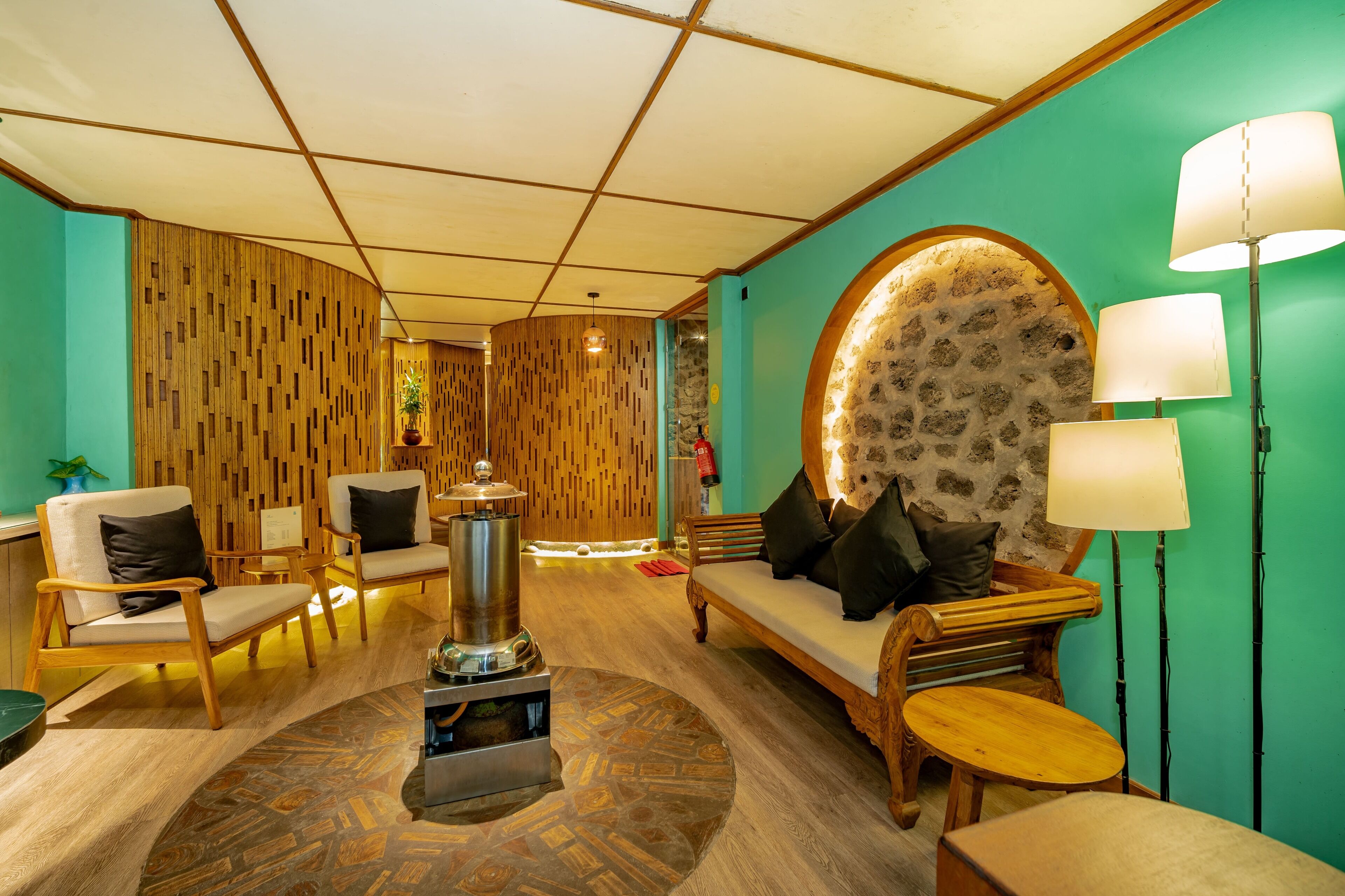 Un espace salon accueillant, doté de meubles en bois, d’une table basse centrale et d’un mur décoratif en pierre.
