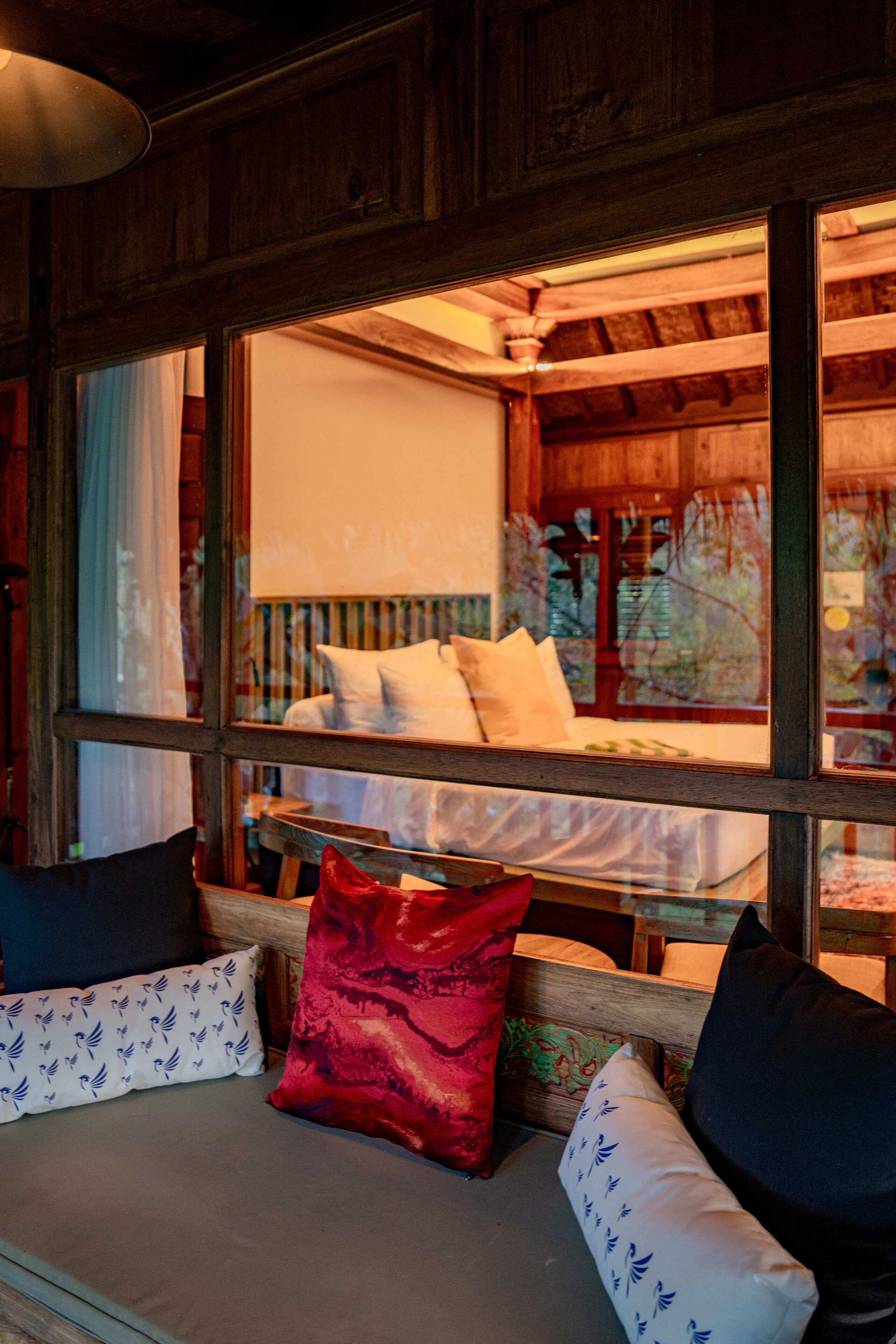 A cozy room with a wooden ceiling, a bed with white bedding, and a bench with cushions.