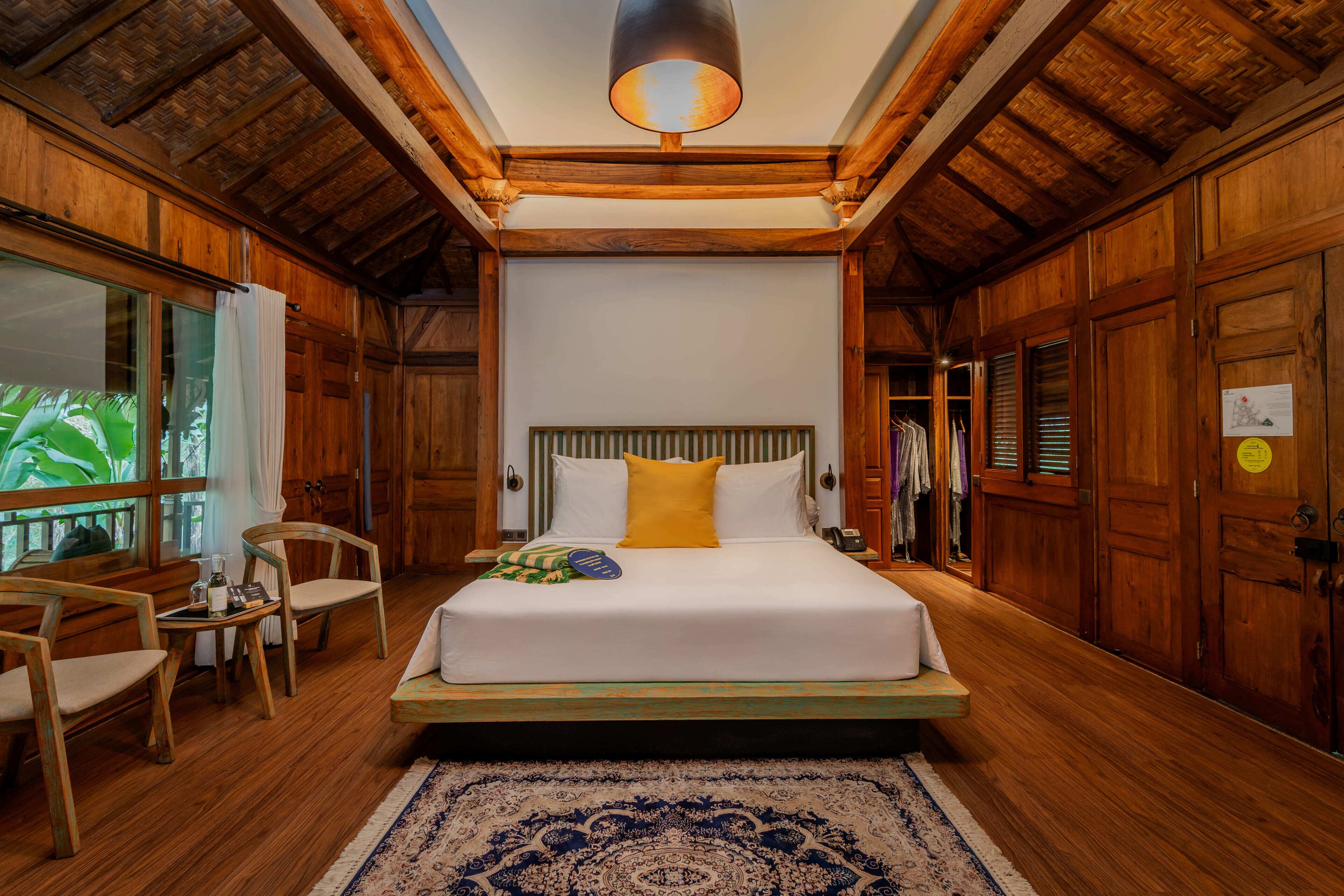 Un dormitorio de estilo rústico con una cama grande, un banco y una mesita.