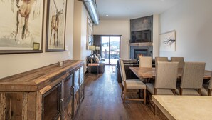 Un interior moderno con una mesa de comedor de madera, sillas, una chimenea y obras de arte en las paredes.