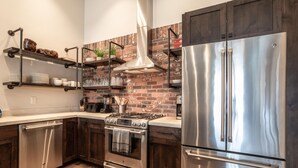 Una cocina moderna con electrodomésticos de acero inoxidable, armarios de madera y un salpicadero de ladrillo.