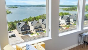 Habitación con amplias ventanas que dan a un área residencial y una masa de agua.