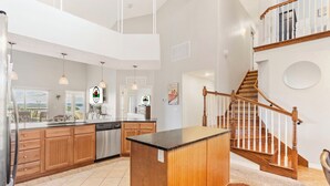 Una cocina amplia con armarios de madera, una isla central y una escalera de madera.