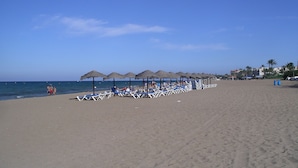 A beach with rows of sun loungers and thatched umbrellas. - 120 Las Velas, 58 (Denia)