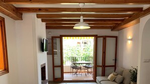 A spacious living area with a wooden ceiling, a dining table with chairs, a sofa, and a TV mounted on the wall. - 120 Las Velas, 58 (Denia)