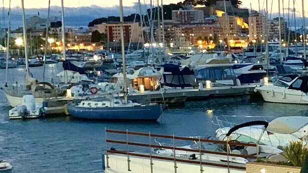A marina with multiple boats docked, a waterfront promenade, and buildings in the background. - 120 Las Velas, 58 (Denia)