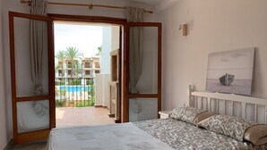 A hotel room with a bed, a view of a pool, and a balcony. - 120 Las Velas, 58 (Denia)