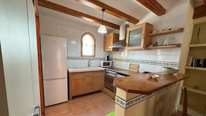 A kitchen with wooden cabinets, a microwave, a sink, and a window. - 117 Las Velas, 57 (Denia)