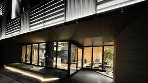 A modern building with large glass windows, a well-lit entrance, and a stone pathway leading to the door. - R Hotel Namba (Osaka)