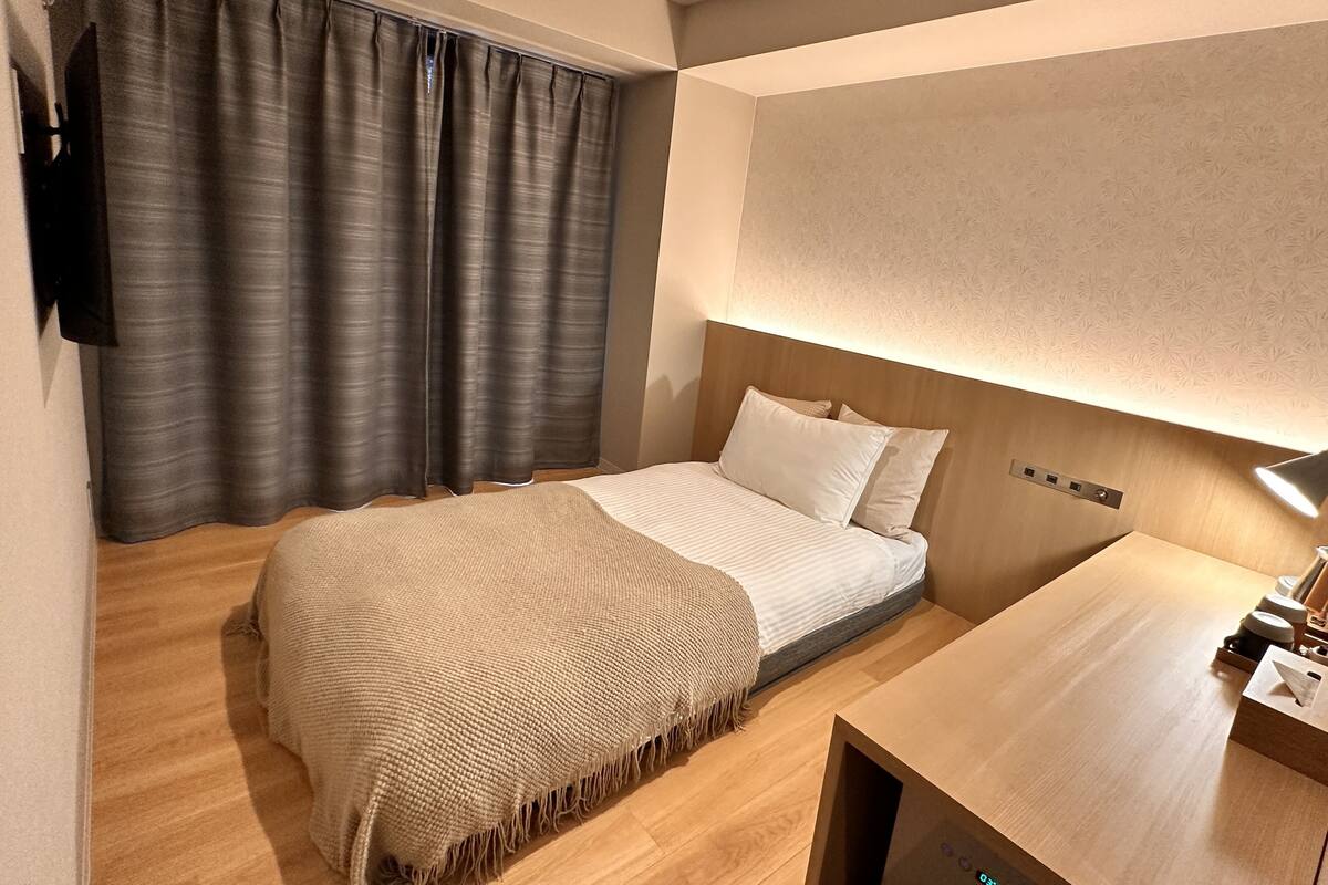 A modern bedroom with a bed, a bedside table, a lamp, and a wall-mounted TV.