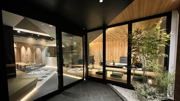 A modern interior with a dining area, seating, and a large window overlooking a garden. - R Hotel Namba (Osaka)