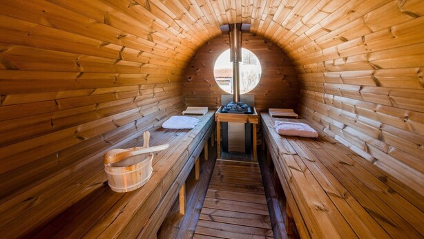 A sauna with wooden benches, a central heating column, and a circular skylight. - Ecolodge in Remouchamps with sauna (Remouchamps)