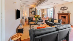A modern living room with a fireplace, leather sofas, and a stone accent wall. - Ecolodge in Remouchamps with sauna (Remouchamps)