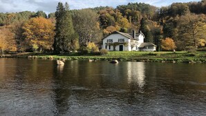A white building with a chimney, surrounded by trees and a body of water. - Ecolodge in Remouchamps with sauna (Remouchamps)