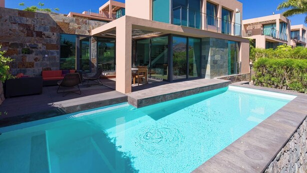 Uma casa moderna com piscina, janelas amplas e área de estar externa.