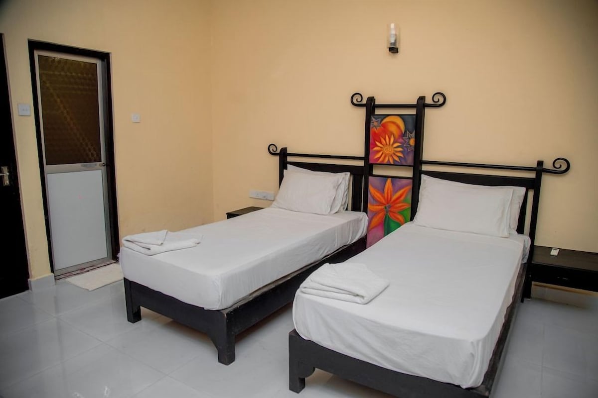 A room with two single beds, a door, and a wall-mounted artwork.